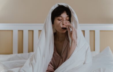 Woman drinking wine, alcohol in bed