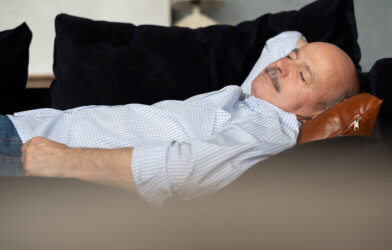 Older man napping, sleeping on couch