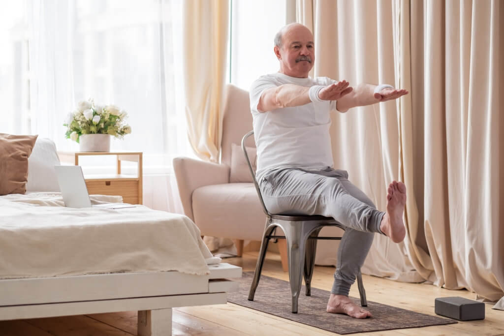 Older man doing chair yoga with online class