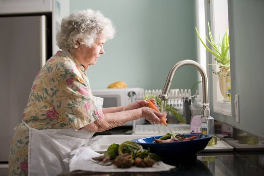 Older woman washing vegetables