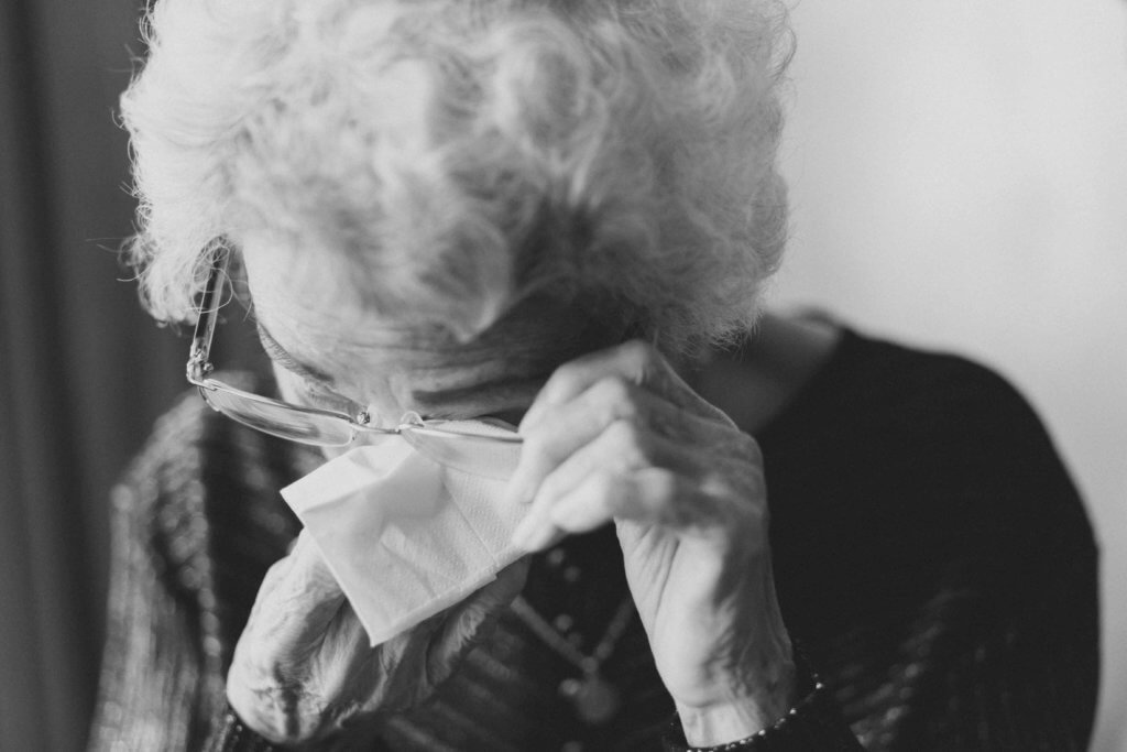 Elderly woman wiping a tear from her eyes