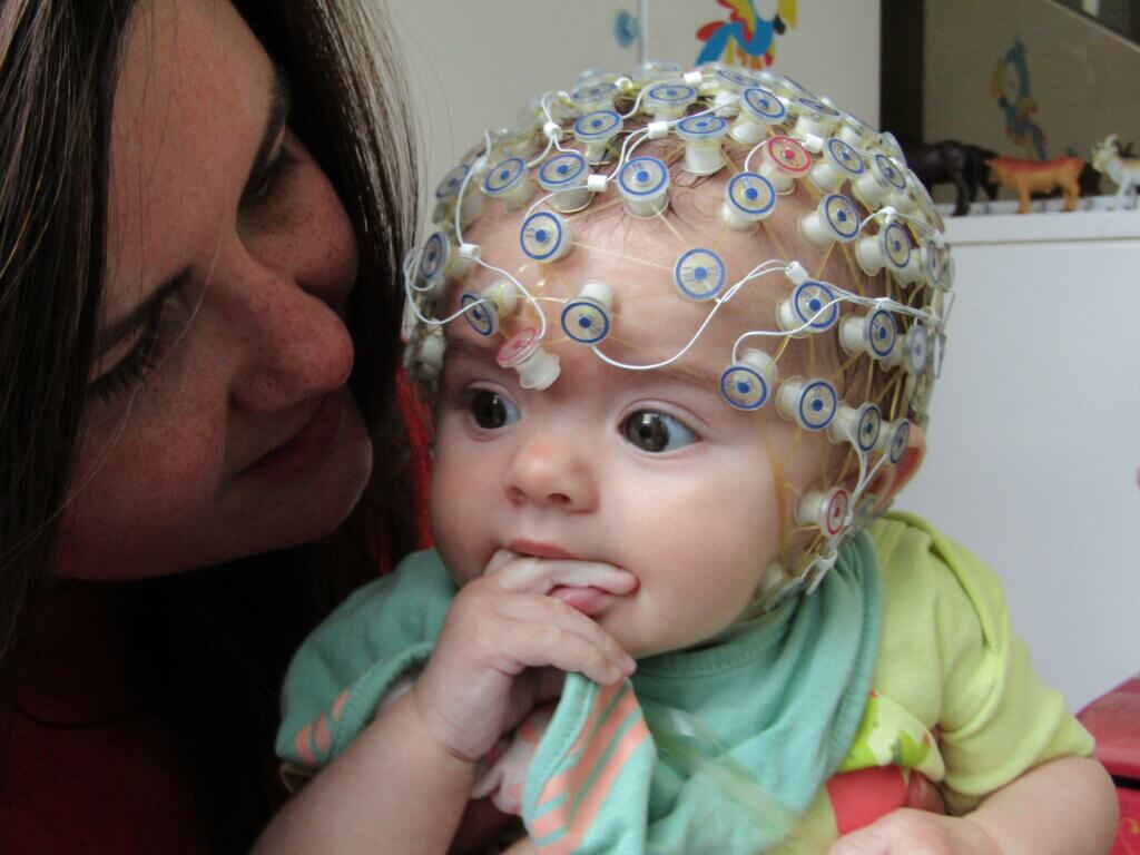 Baby wearing EEG cap for the study. Pictured with parent.