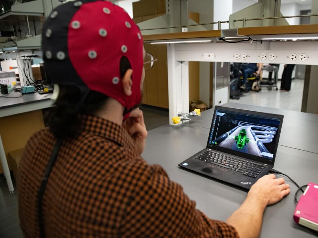 Hussein Alaouie, a graduate student in Jose del R. Millan's lab, wears a hat filled with electrodes connected to a computer.