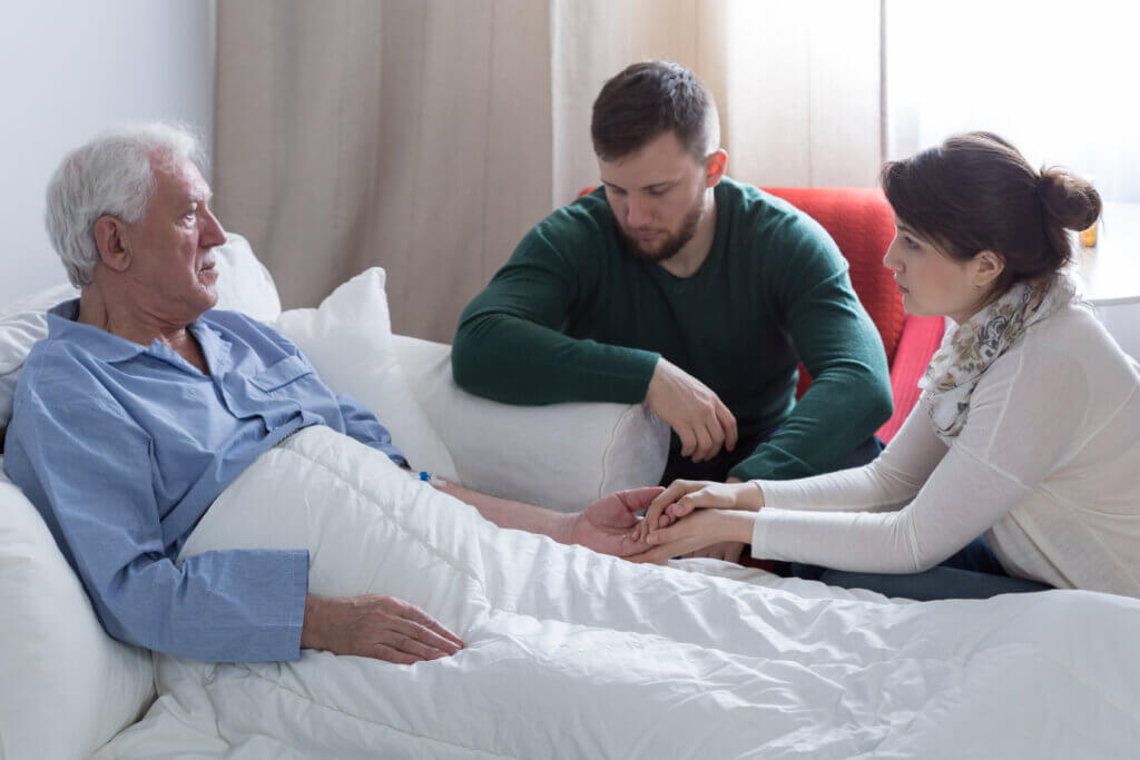 Elderly man sick in bed with adult children by his side