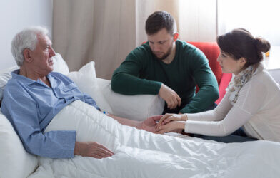 Elderly man sick in bed with adult children by his side
